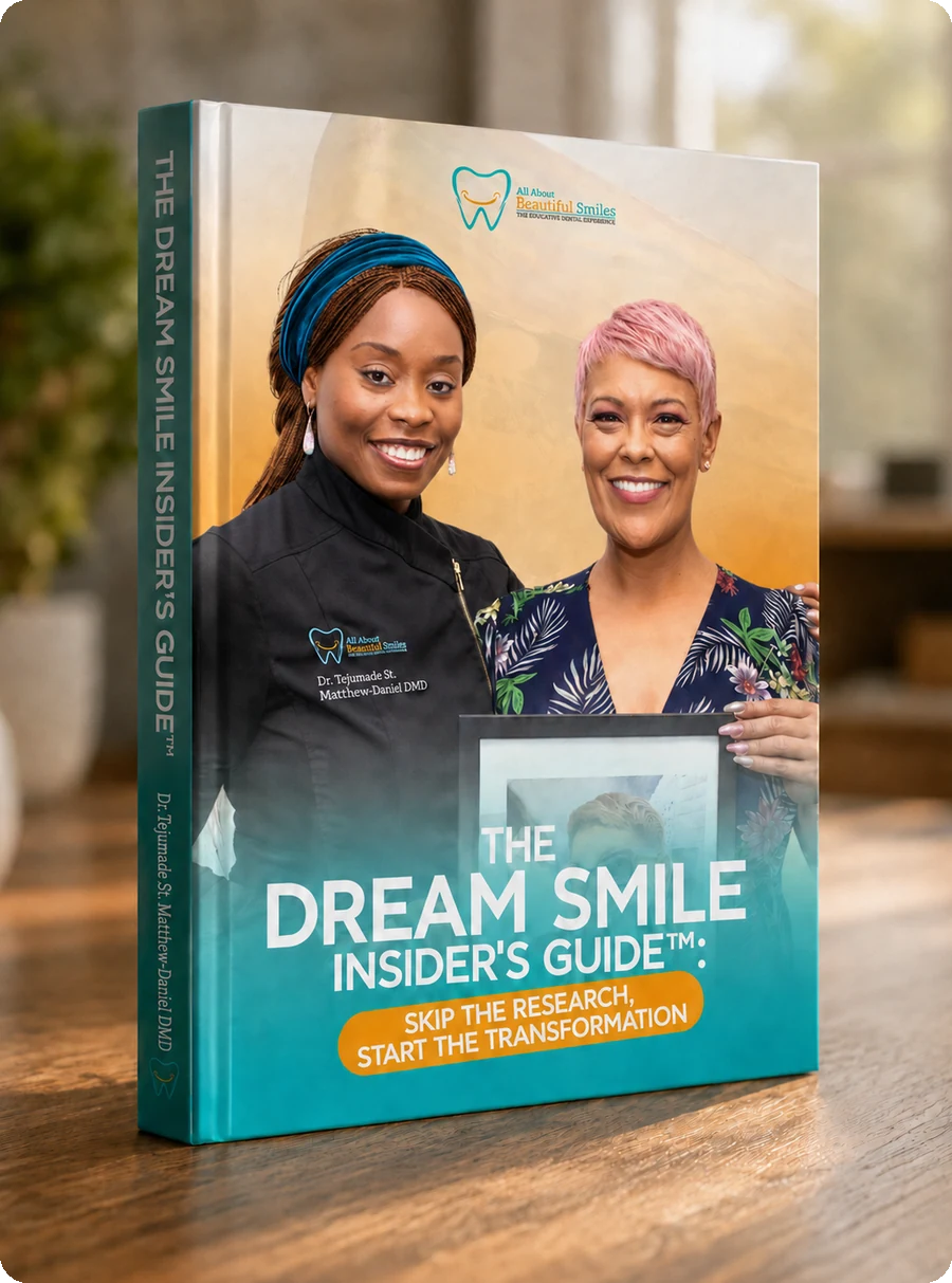 The Dream Smile Insider's Guide as a printed book standing on a desk. The cover shows Dr. Tejumade St. Matthew-Daniel with a smiling patient holding a framed photo of her earlier smile.
