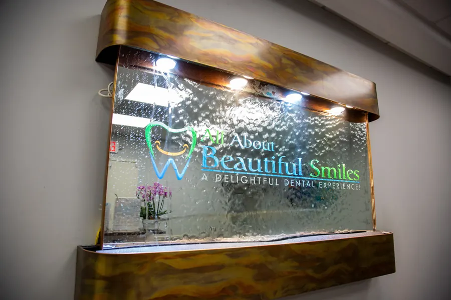 The All About Beautiful Smiles logo on the water-feature wall in the office